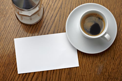 close up of a coffee cup and a blank card on a table